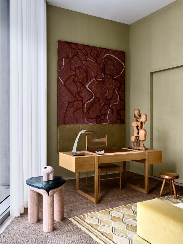 Home office in a top-floor Hudson River penthouse with oak writing desk, sculptural lamp, and bold red artwork with curated modern sculpture.