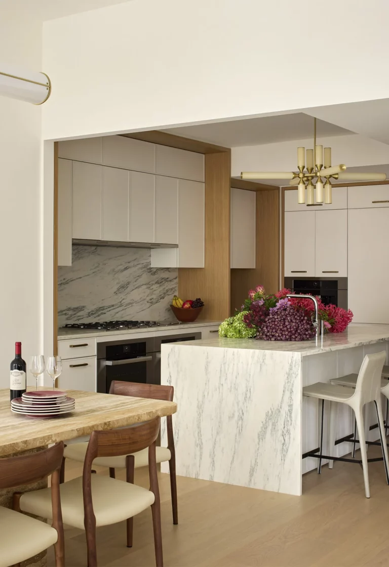Kitchen and breakfast area in a Snøhetta Upper West Side residence with a stone waterfall island, integrated cabinetry, and an everyday dining table designed for family use.