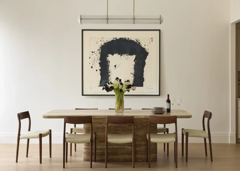 Breakfast room in a Snøhetta Upper West Side residence featuring a monolithic stone table, walnut chairs, and curated artwork in a light-filled everyday dining setting.