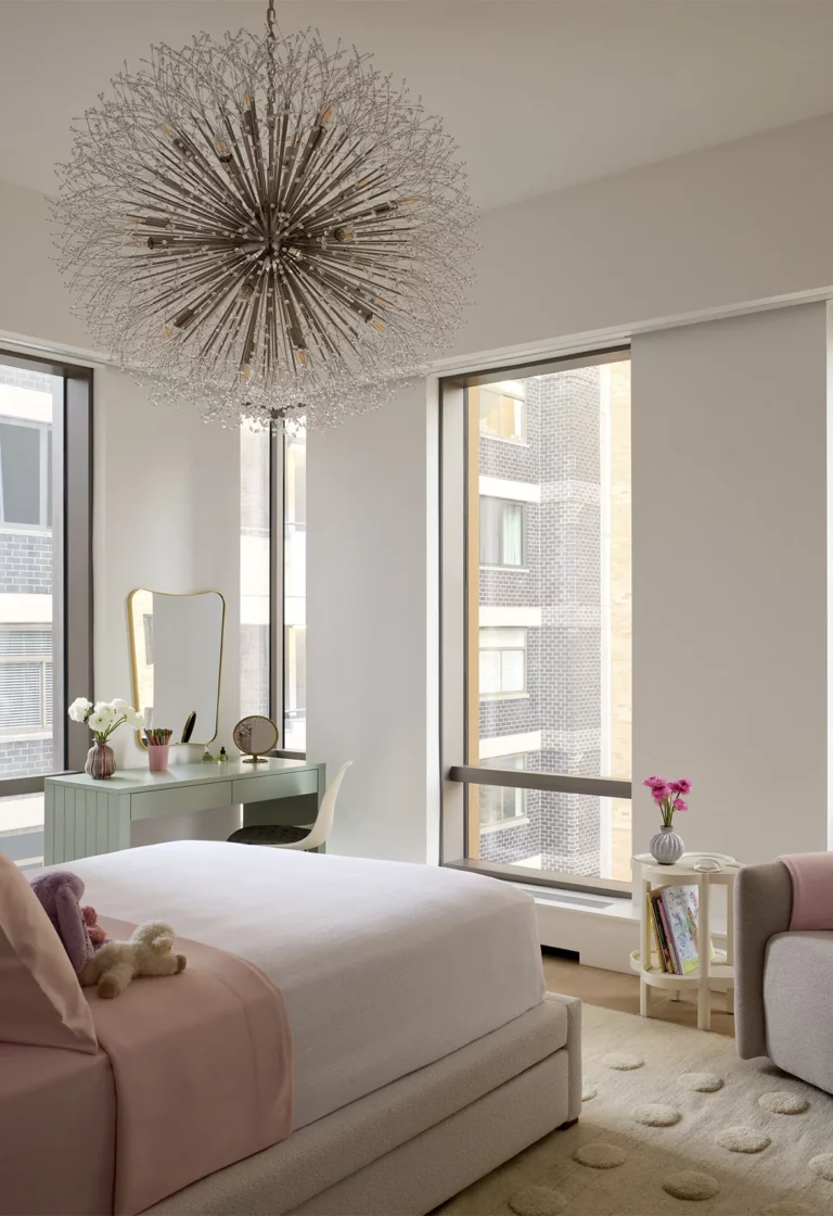Guest bedroom in a Snøhetta Upper West Side apartment with corner windows, a sculptural chandelier, and a mint-green writing desk with mirror.