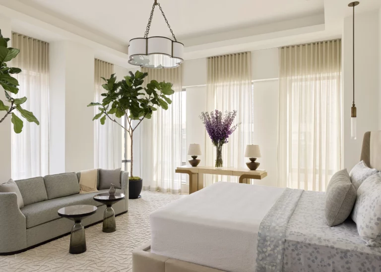 Principal bedroom suite in a Snøhetta Upper West Side apartment with a sitting area, floor-to-ceiling curtains, and multiple exposures that fill the room with soft natural light.